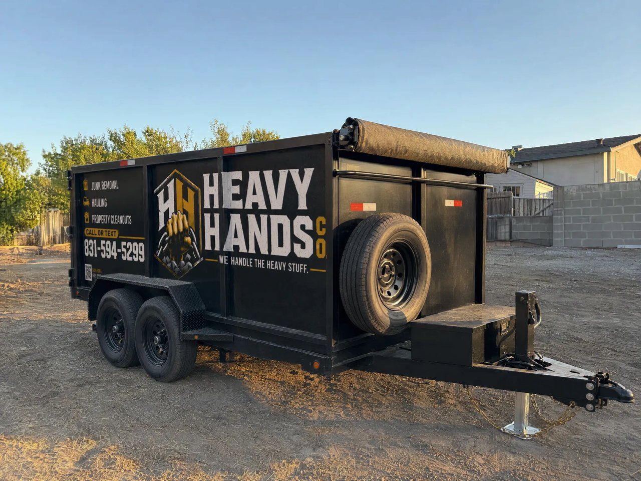 Empty black Heavy Hands Co. 12 by 8 by 4 foot dump trailer ready for a job